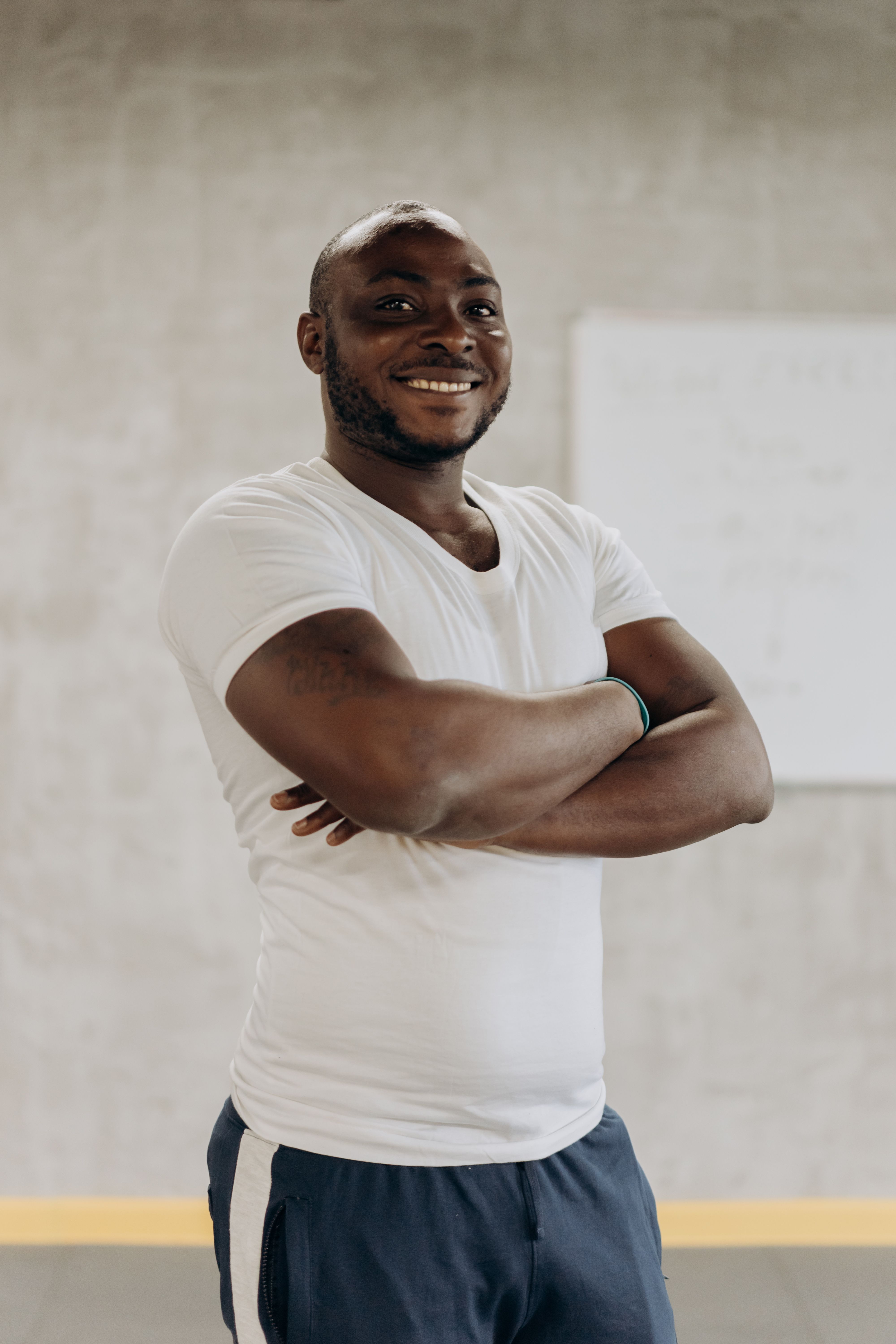 A smiling young adult man poses confidently indoors in casual attire, representing healthy lifestyle and happiness.