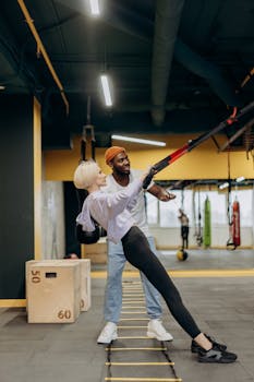A young woman engaging in a fitness routine with a trainer using resistance bands indoors.