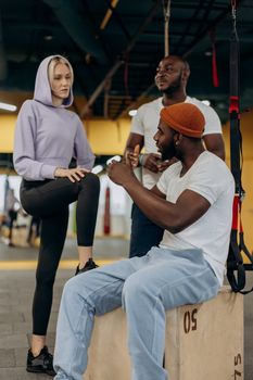 A diverse group of adults discussing workout routines in a modern gym setting.