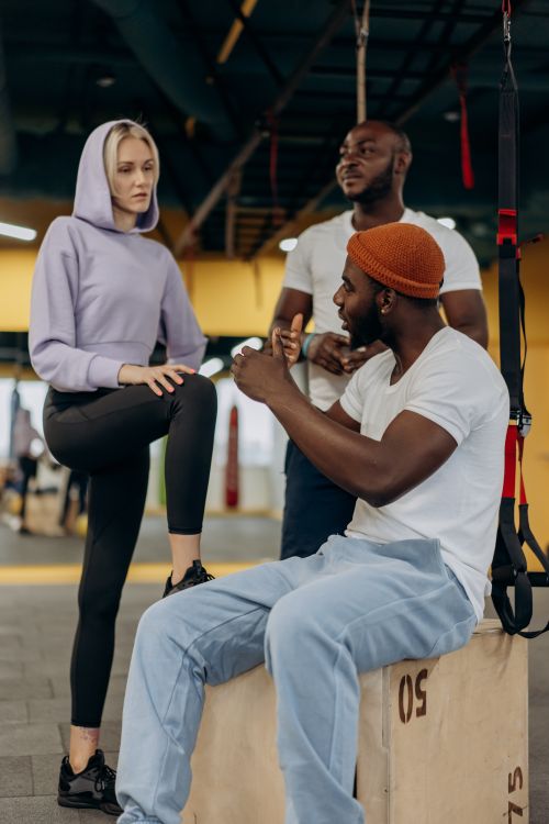 Free A diverse group of adults discussing workout routines in a modern gym setting. Stock Photo