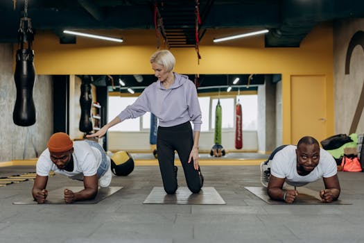 A diverse group doing planks during a guided fitness session in a gym.