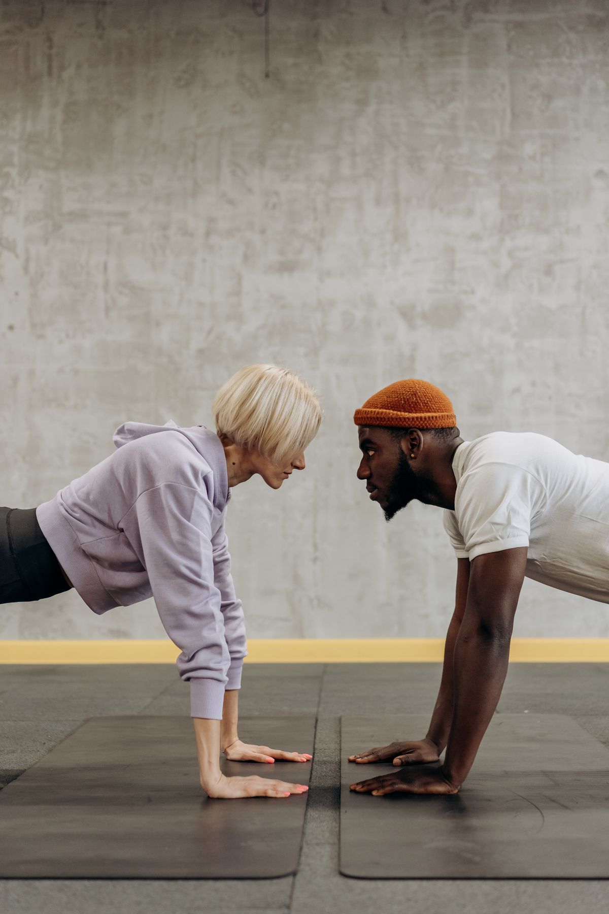 Two people doing push-ups face to face on exercise mats