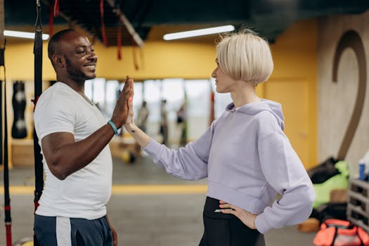 A man and woman exchanging a high-five in a gym, symbolizing teamwork and motivation.