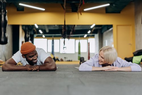Free Two friends smiling and exercising together at a gym, promoting fitness and healthy lifestyle. Stock Photo