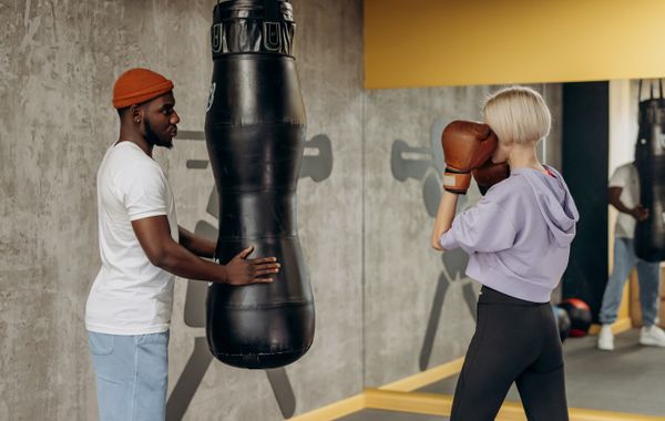 Deux adultes a l'entraînement de boxe avec un sac de frappe