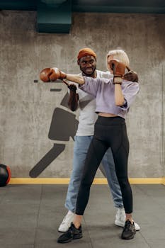 A woman trains in boxing with a coach at a gym, focusing on fitness and technique.