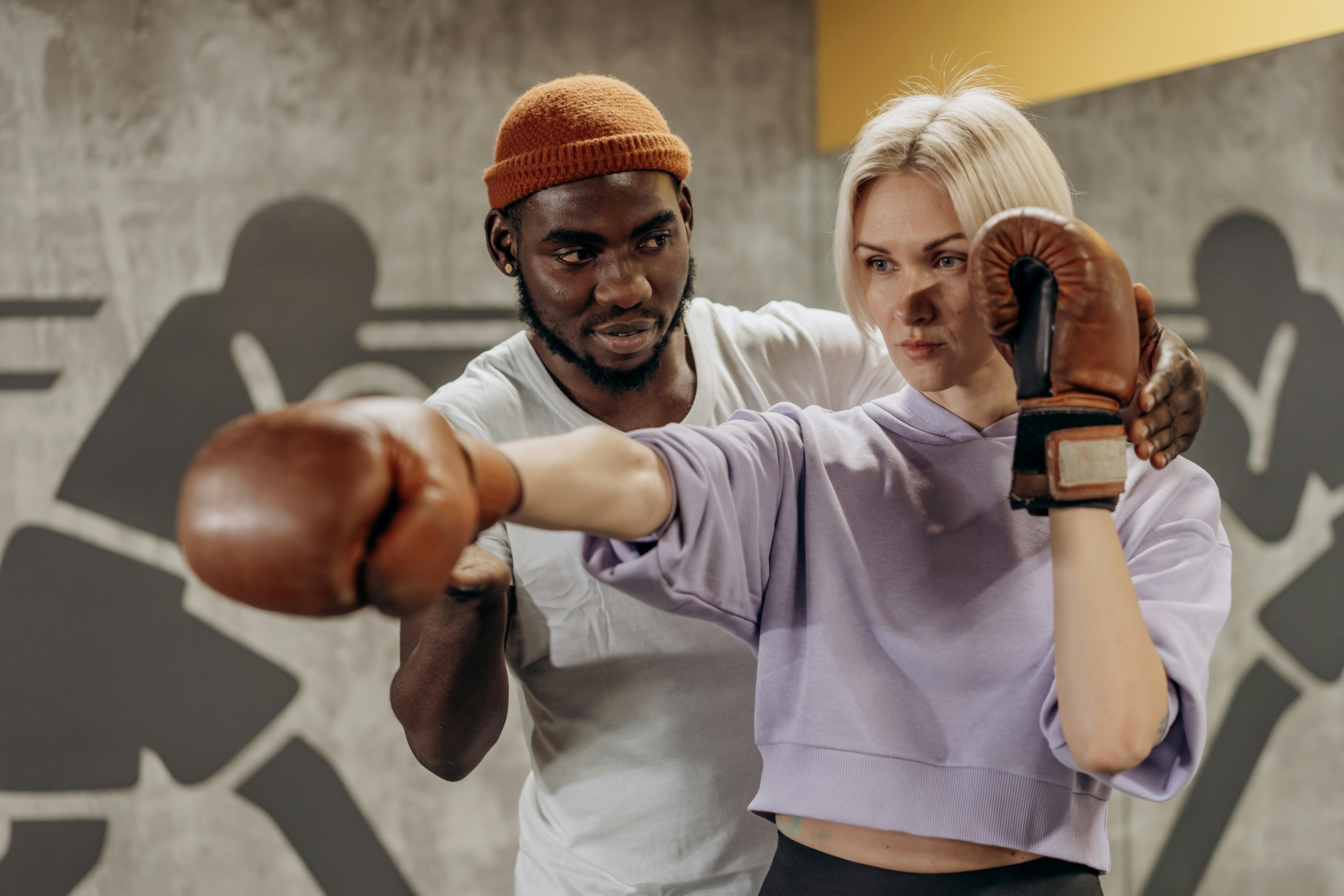 A trainer guides a boxer's punching technique during an indoor gym session.