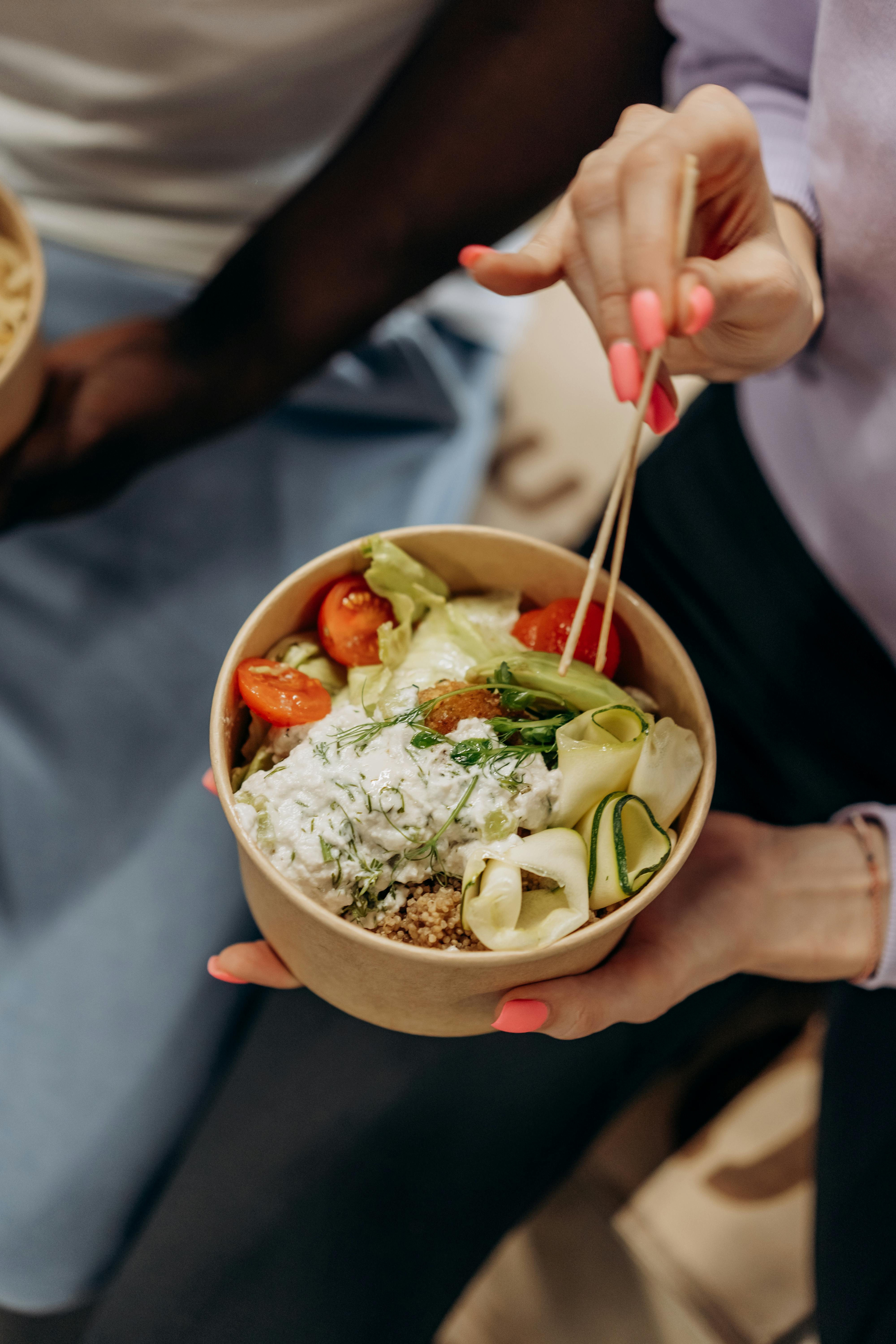 person holding a bowl with vegetable salad