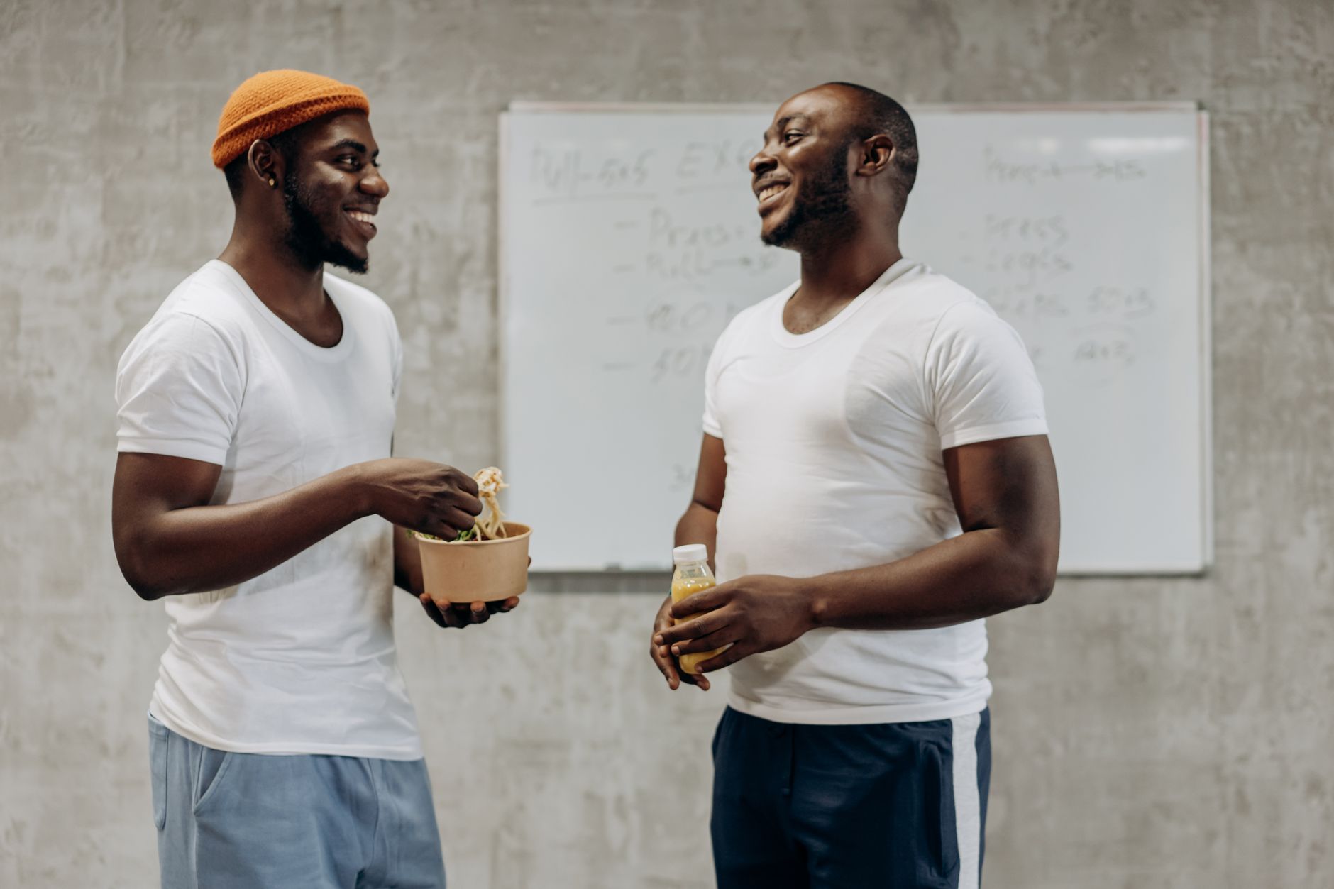 Two friends enjoying a healthy snack and drink indoors, sharing smiles and a moment of happiness.