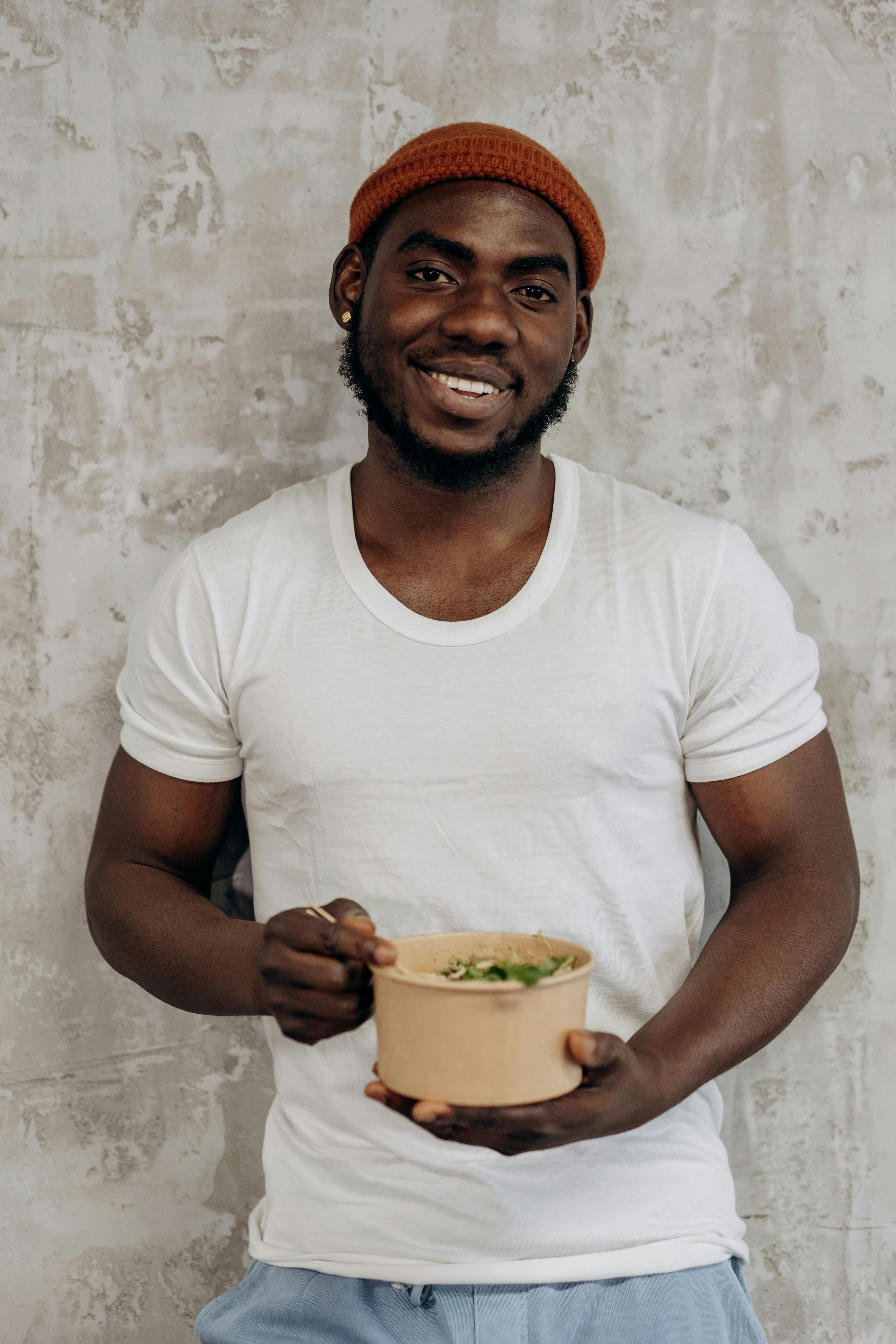 man in white crew neck t shirt holding a rice bowl