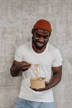 Happy man eating a bowl of noodles, embracing a healthy lifestyle.