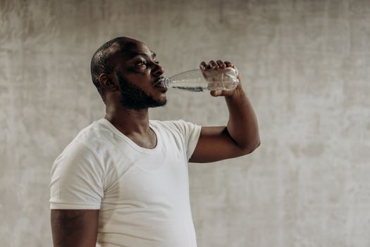 Healthy living concept: Man staying hydrated with water. Indoors, fitness focus.