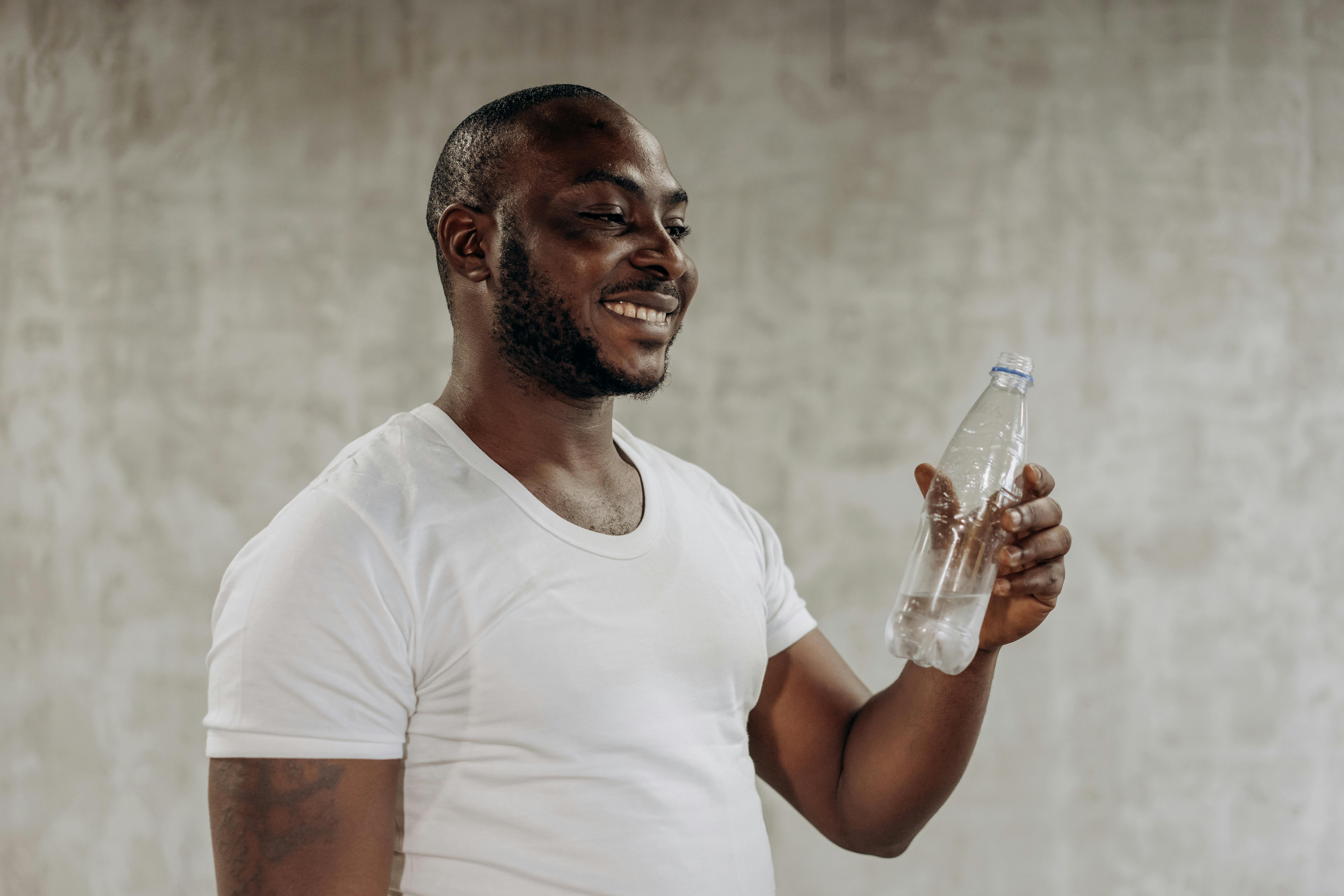 Young fitness black man holding a water bottle impressed holding copy space  on palm. Stock Photo