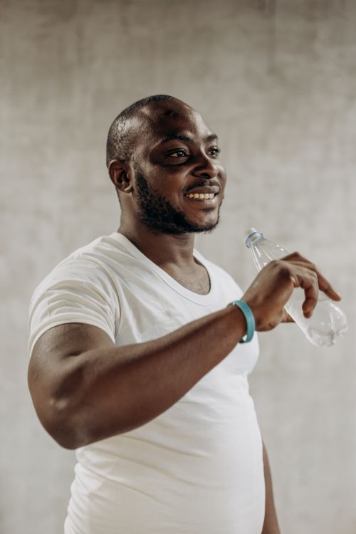 Free Smiling man in white shirt holding a water bottle indoors. Stock Photo