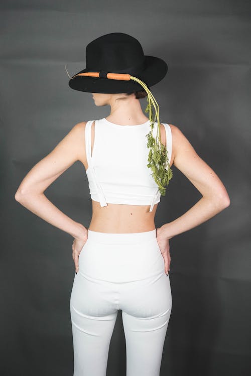 Woman in White Tank Top and White Leggings with her Hands on her Waist