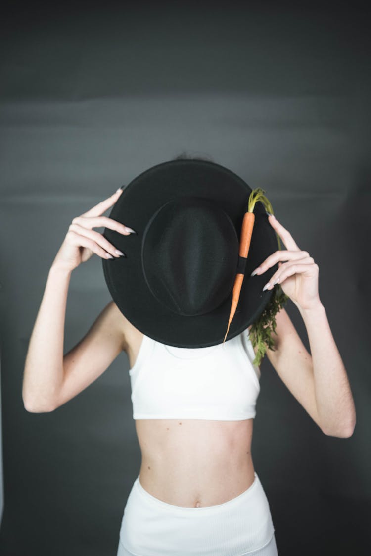 Person Holding Black Fedora Hat With Carrot 