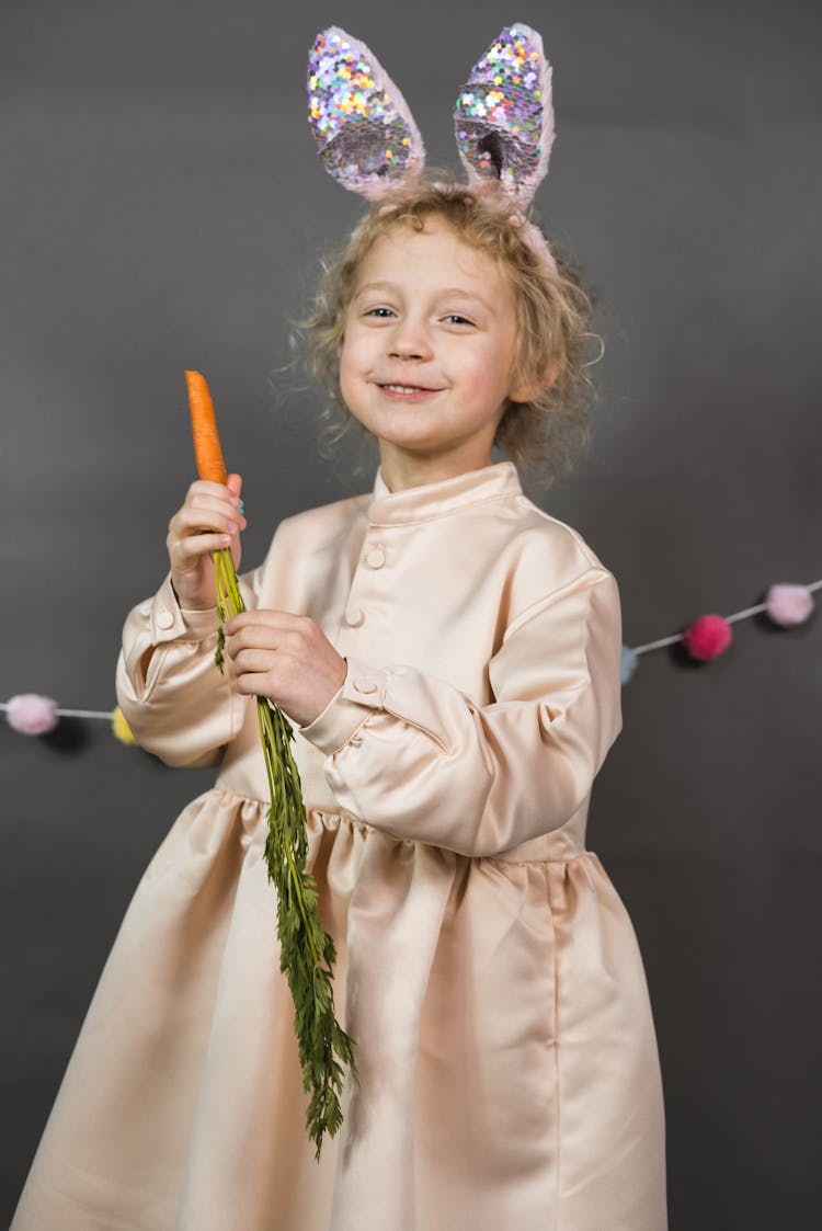 Child Wearing A Dress Holding A Carrot