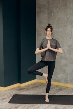 A woman performs a tree pose, enhancing balance and mindfulness indoors.