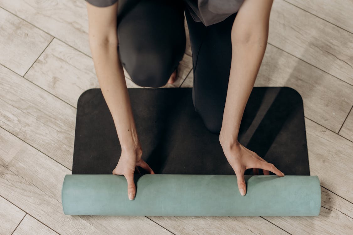 Free Woman in Black Leggings Unrolling A Yoga Mat Stock Photo