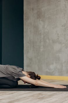 A woman in a relaxed yoga pose indoors, focusing on flexibility and mindfulness.