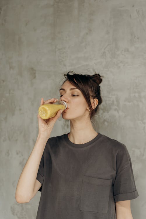 Woman in Black Crew Neck T-shirt Drinking Juice