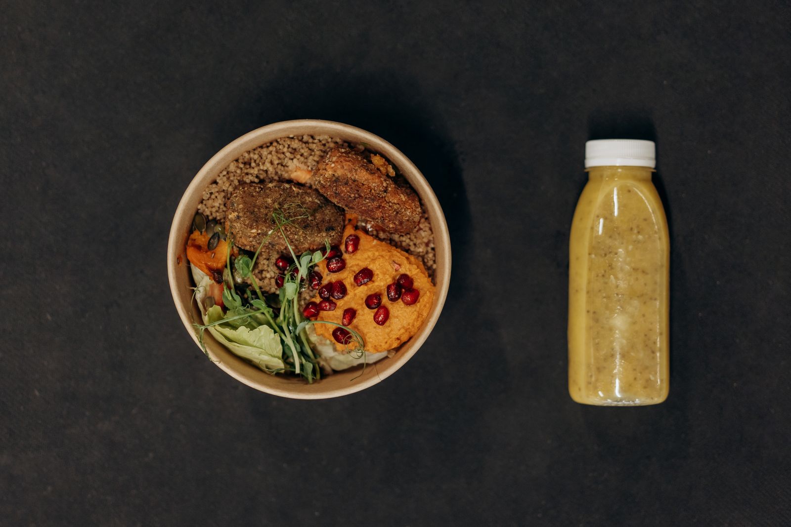 A high-fiber lunch bowl of whole grains, bean patties, greens, and pomegranate seeds, the kind of meal that fills a woman over 40 up for longer