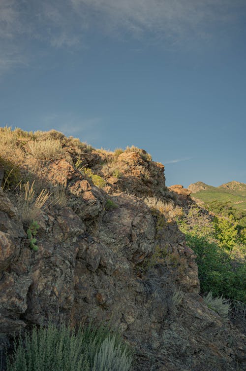 Green Grass and Brown Rock Formation Under Blue Sky