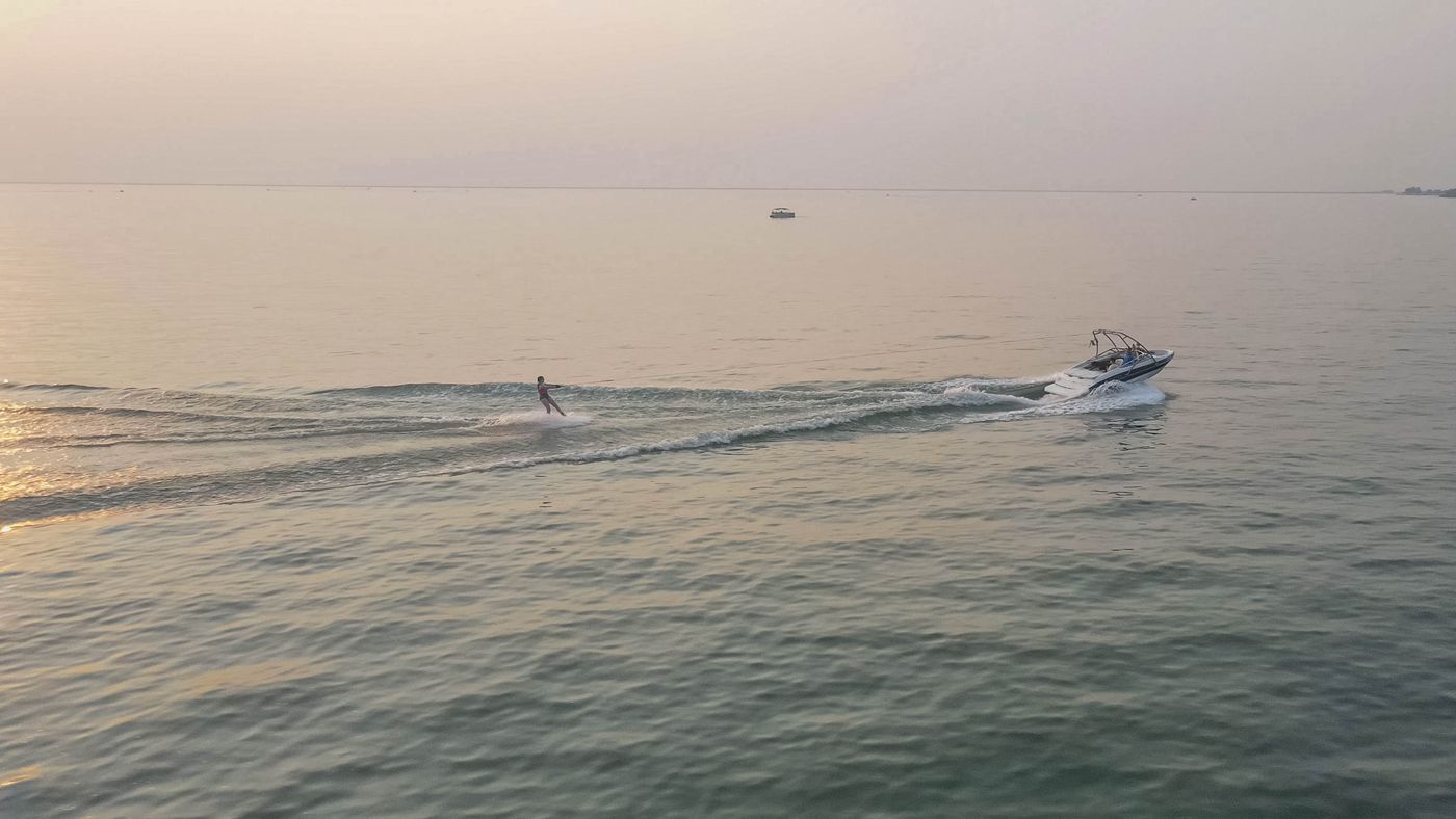 Speedboat and wakeboarder at sunset