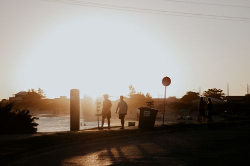 Free Silhouetted people walking by a riverside during a tranquil sunset, capturing serene evening vibes. Stock Photo