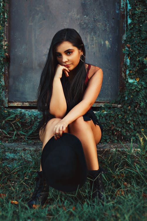 Woman in Black Attire sitting near Leaves 