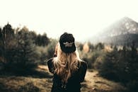 一名戴着黑色帽子、穿着毛衣的女子拥抱户外冒险，欣赏山景