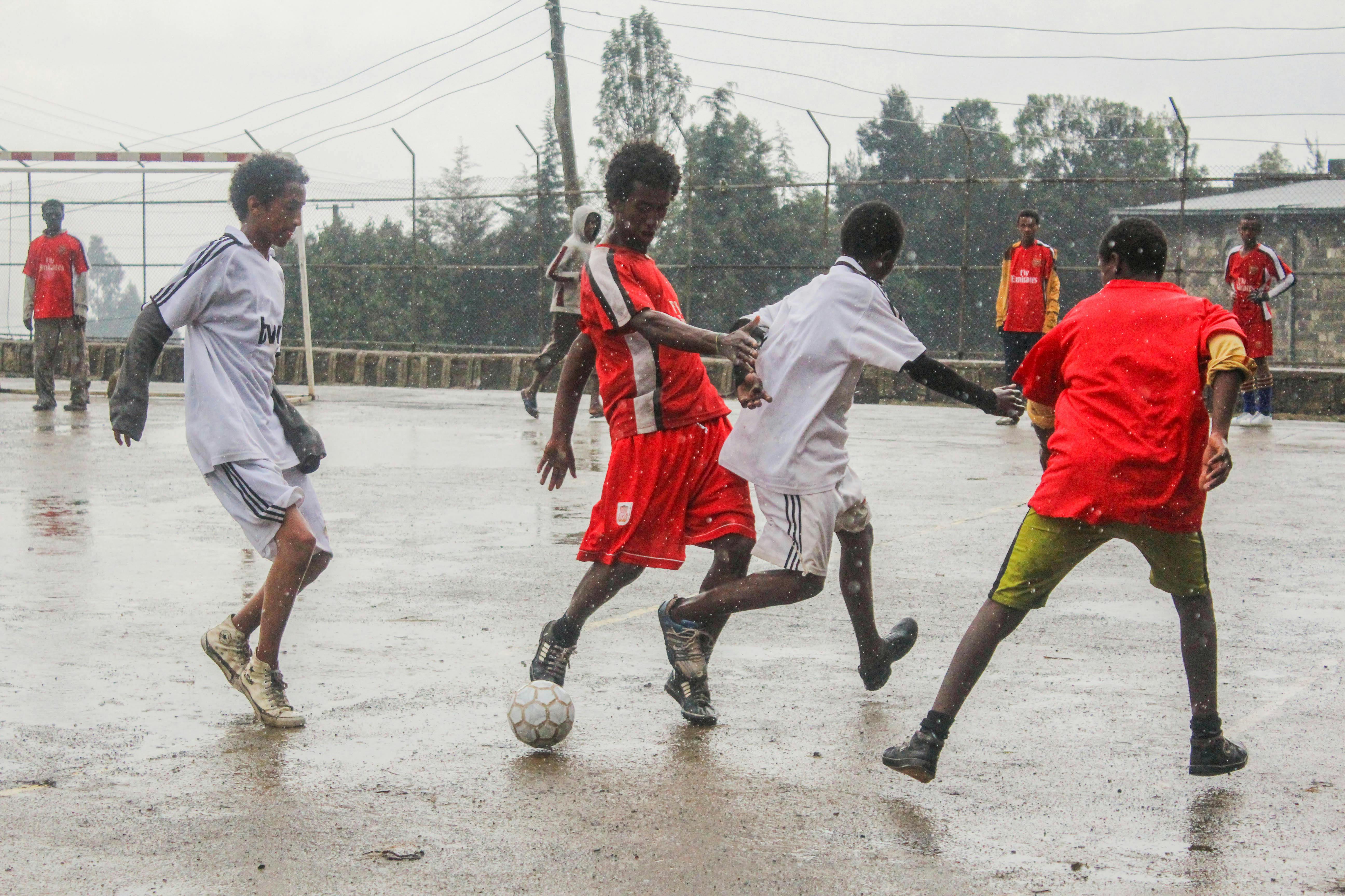 men playing soccer under the rain