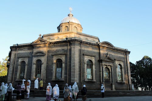 People Walking in Front of Brown Concrete Building