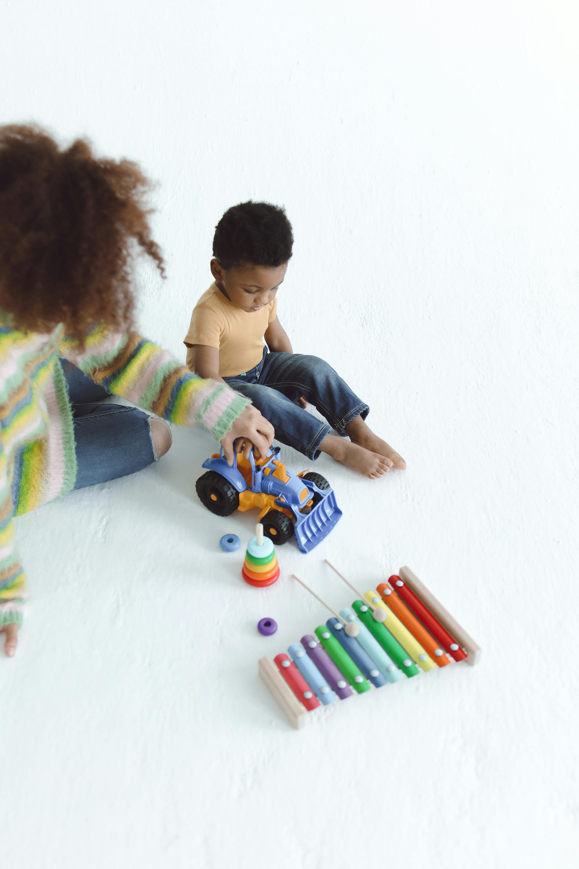 woman playing with a toy truck beside a boy