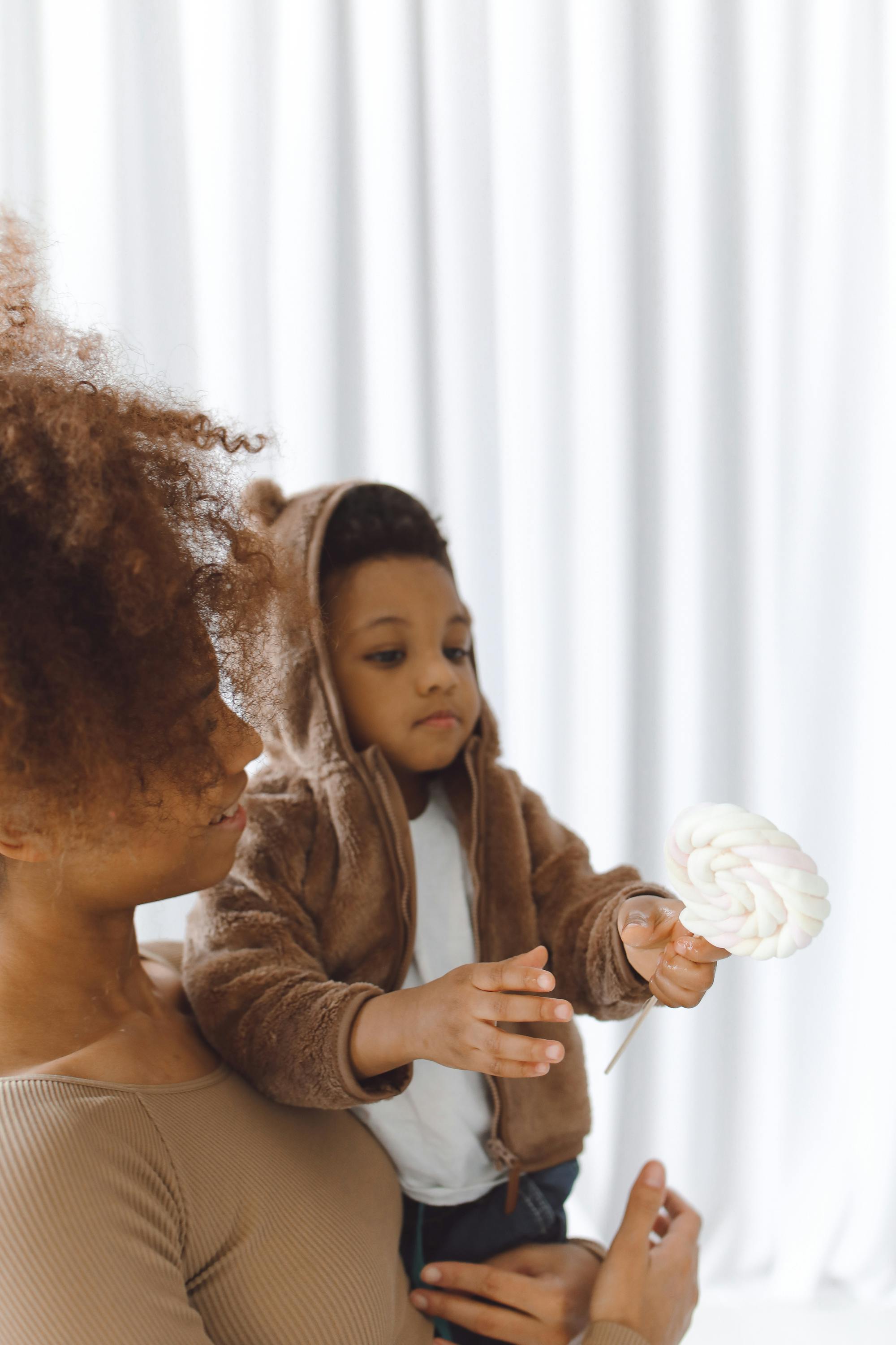 Mother holding her young son with a marshmallow lollipop.