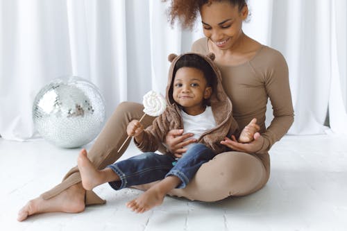 Free Boy Eating Marshmallow Candy While Sitting on the Lap of a Woman Stock Photo