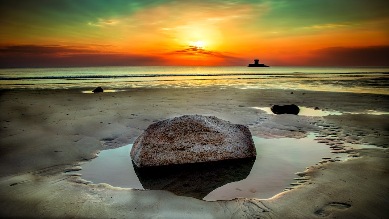 日没時の海岸の横にある石