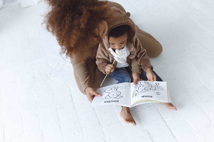 A Woman And A Child Looking At A Picture Book