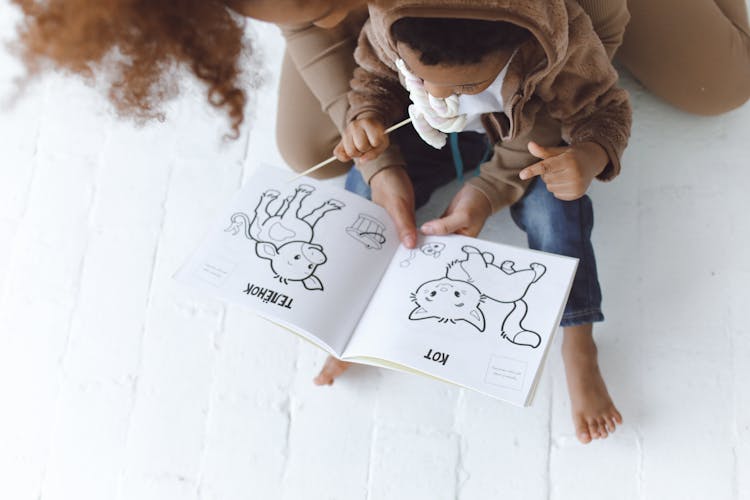 A Child Eating Lollipop Looking At Picture Book