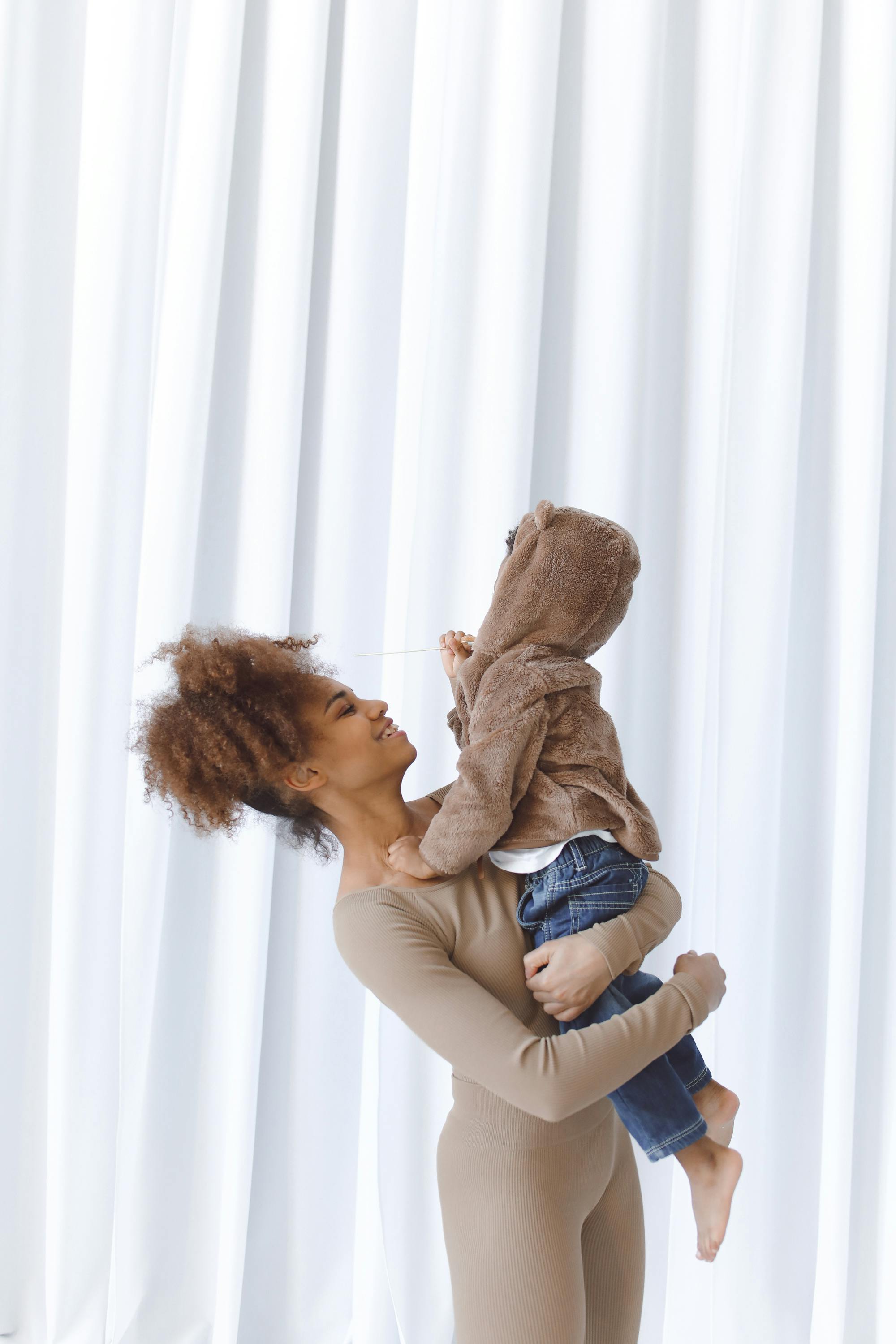 a woman carrying a child wearing a brown hoodie