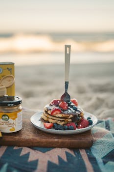 A stack of berry pancakes on the beach during a serene summer morning.