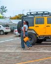 Woman in Blue and White Stripe Pants Standing Beside Yellow Car