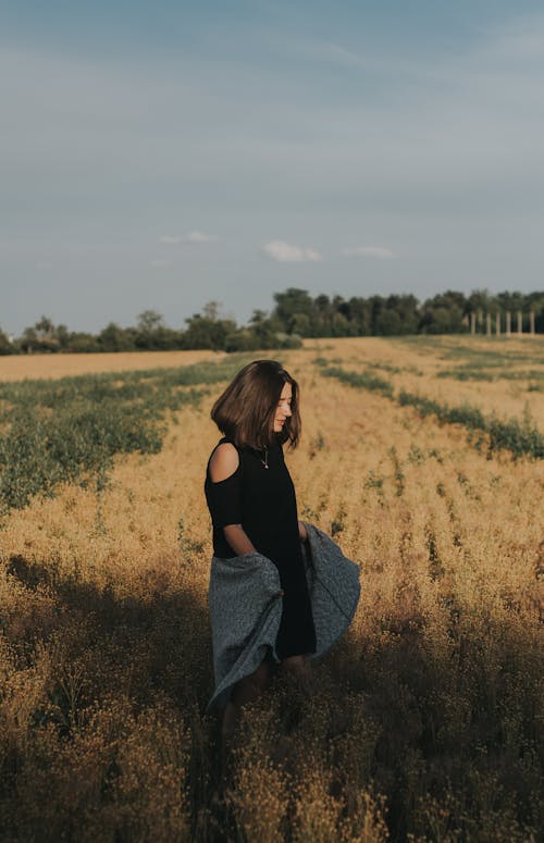 Free Dreamy young woman walking in rural field on sunny day Stock Photo