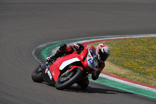Man in Red and Black Motorcycle Suit Riding on Red and White Sports Bike