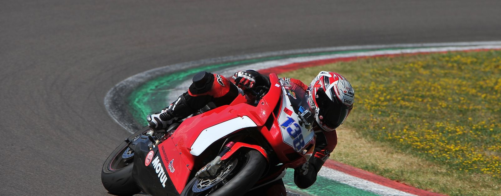 Motorcycle racer taking a sharp turn at Imola Circuit, showcasing high-speed racing action.