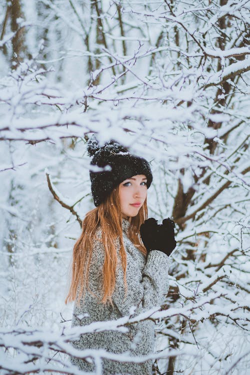Woman in warm clothing standing in snowy forest