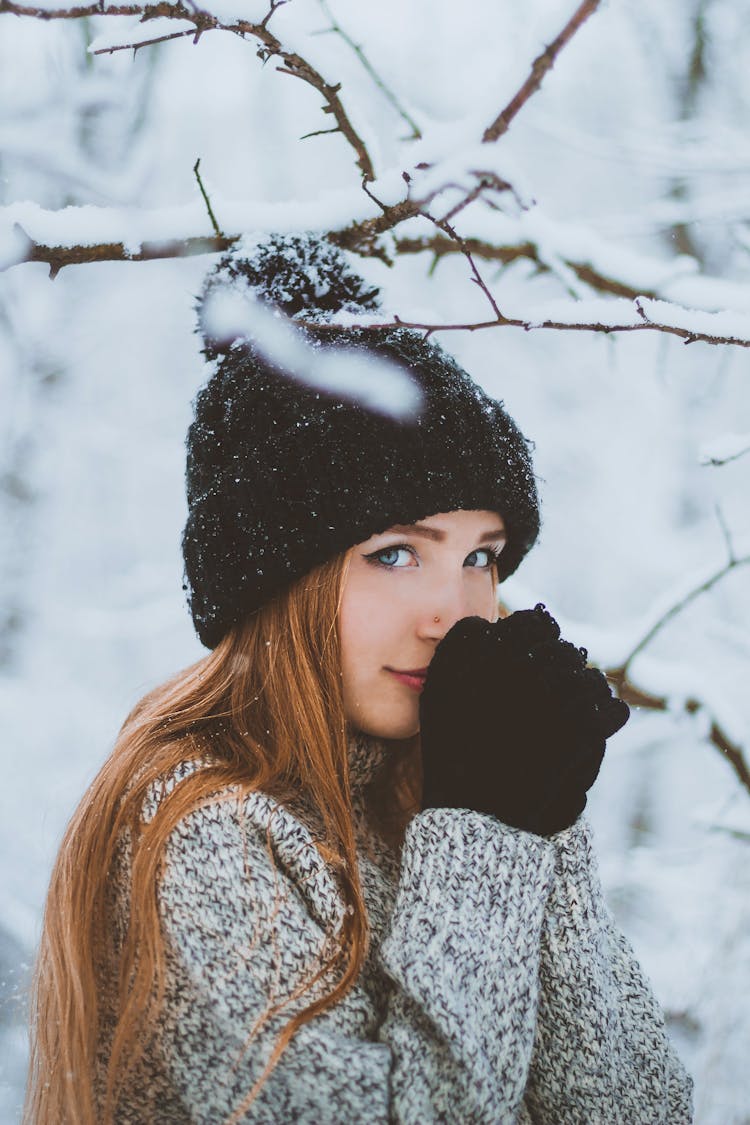 Woman In Warm Hat Gloves And Sweater In Winter Forest