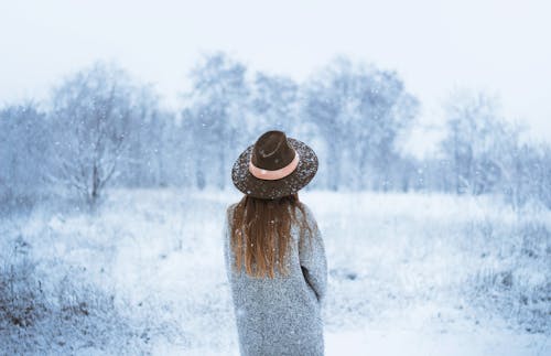 Woman enjoying winter scenery with bare trees under snowfall