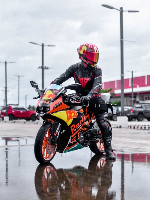 Free A motorcyclist in colorful gear poses on a KTM bike on a reflective wet street. Stock Photo