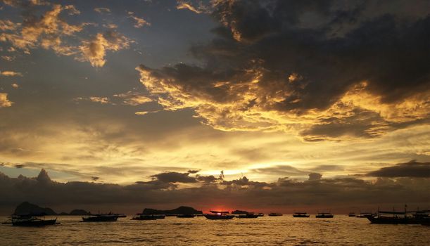 A breathtaking sunset over silhouetted boats in San Antonio, Philippines.
